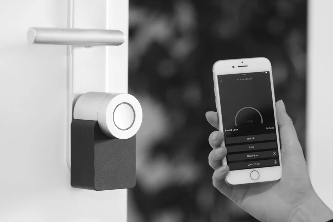 A smart lock mounted beneath a door handle, operated with a phone